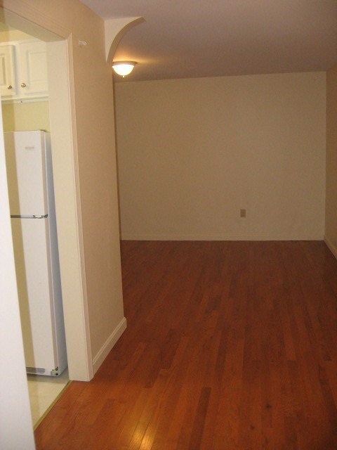 an empty living room with a refrigerator in it