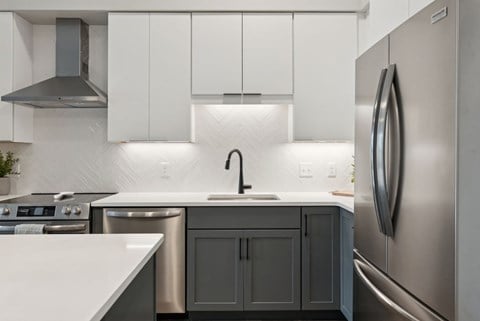 A modern kitchen with a stainless steel refrigerator and a white countertop.