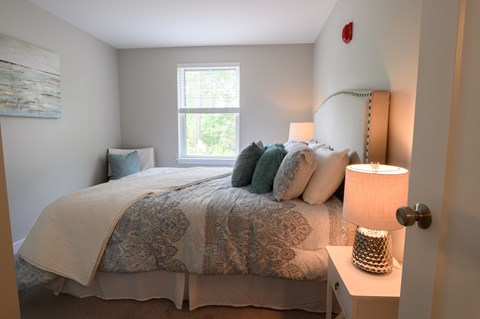 A bedroom with a bed, nightstand, and lamp.