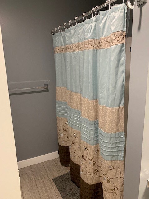 A shower curtain with a blue and beige pattern hangs in a bathroom.