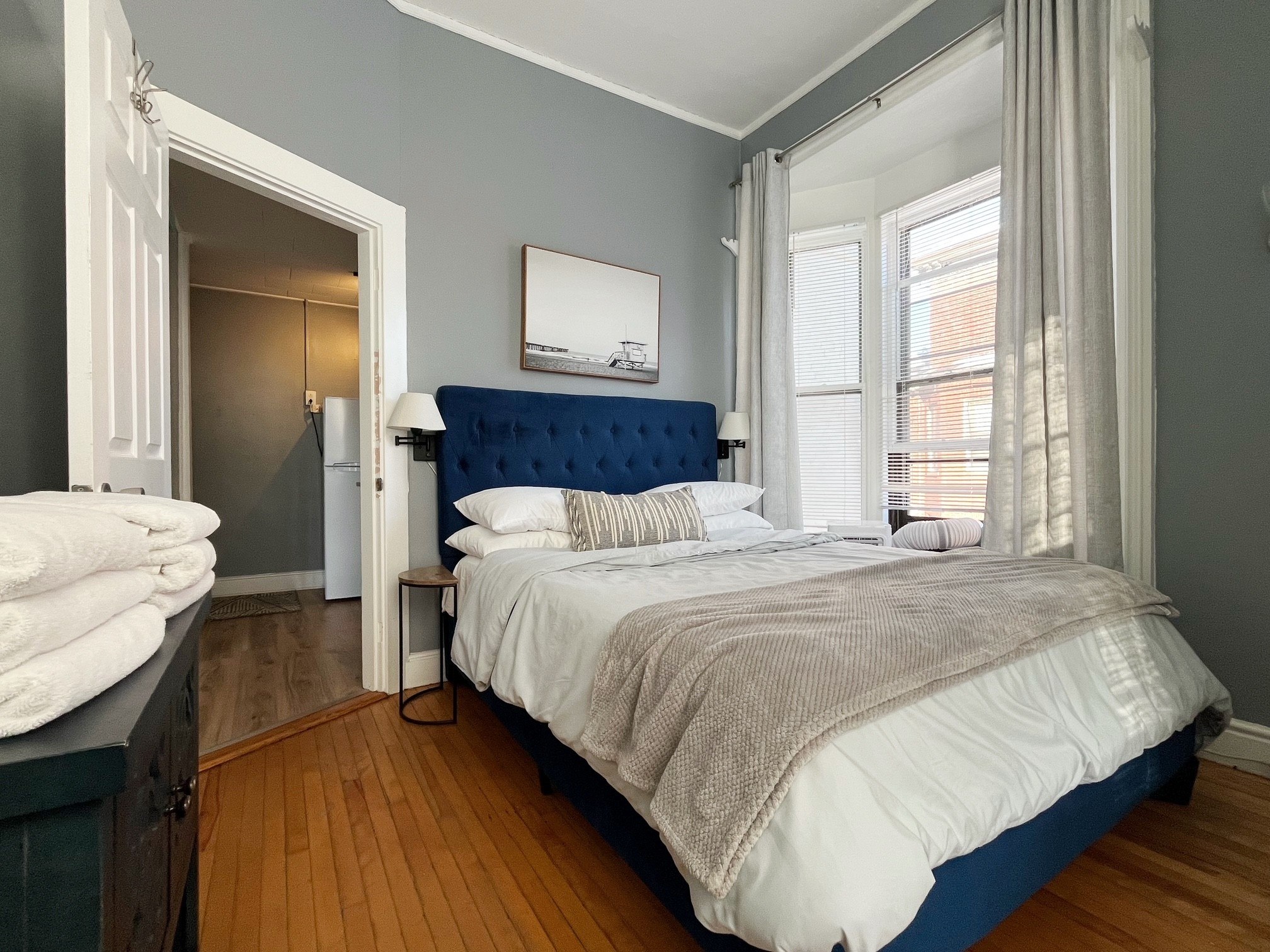 A bedroom with a bed, nightstand, and a painting on the wall.