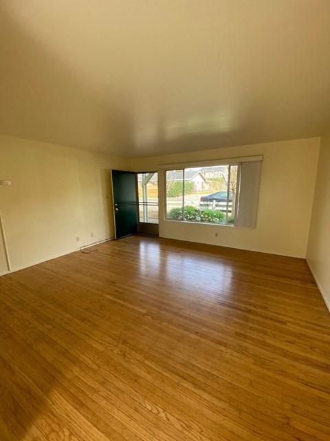 an empty living room with wood floors and a large window