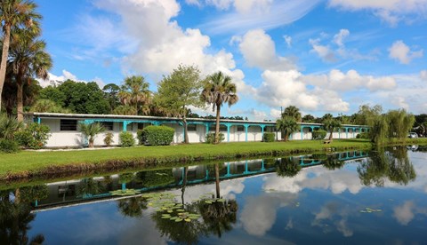 A serene landscape with a building, trees, and a reflective body of water.