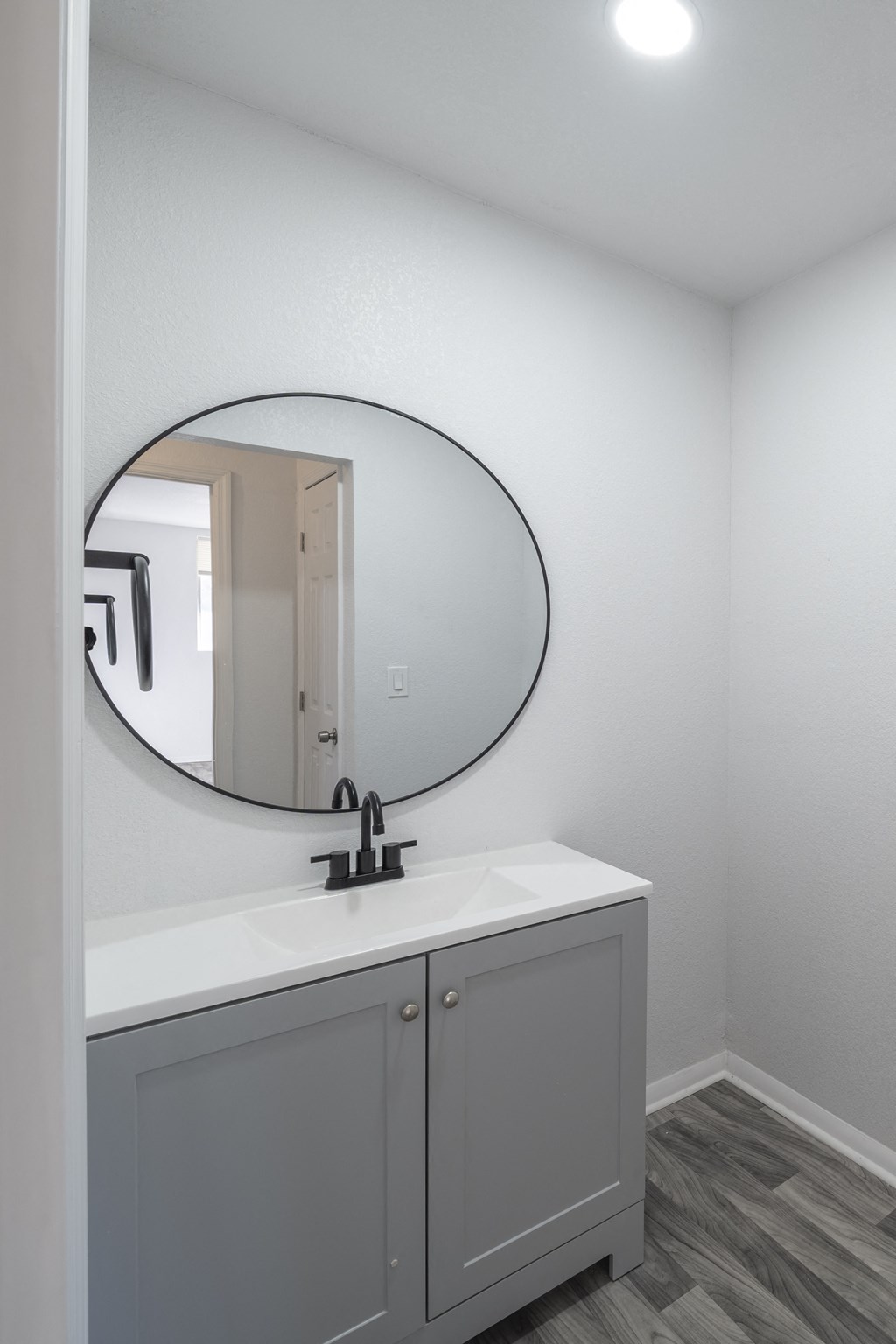 A bathroom with a round mirror above a sink. at Red Bay Apartment Complex, Jacksonville, FL, 32211