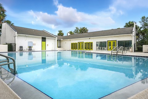 A swimming pool in front of a white building with yellow doors.