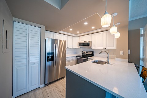 a kitchen with white counter tops and a stainless steel refrigerator