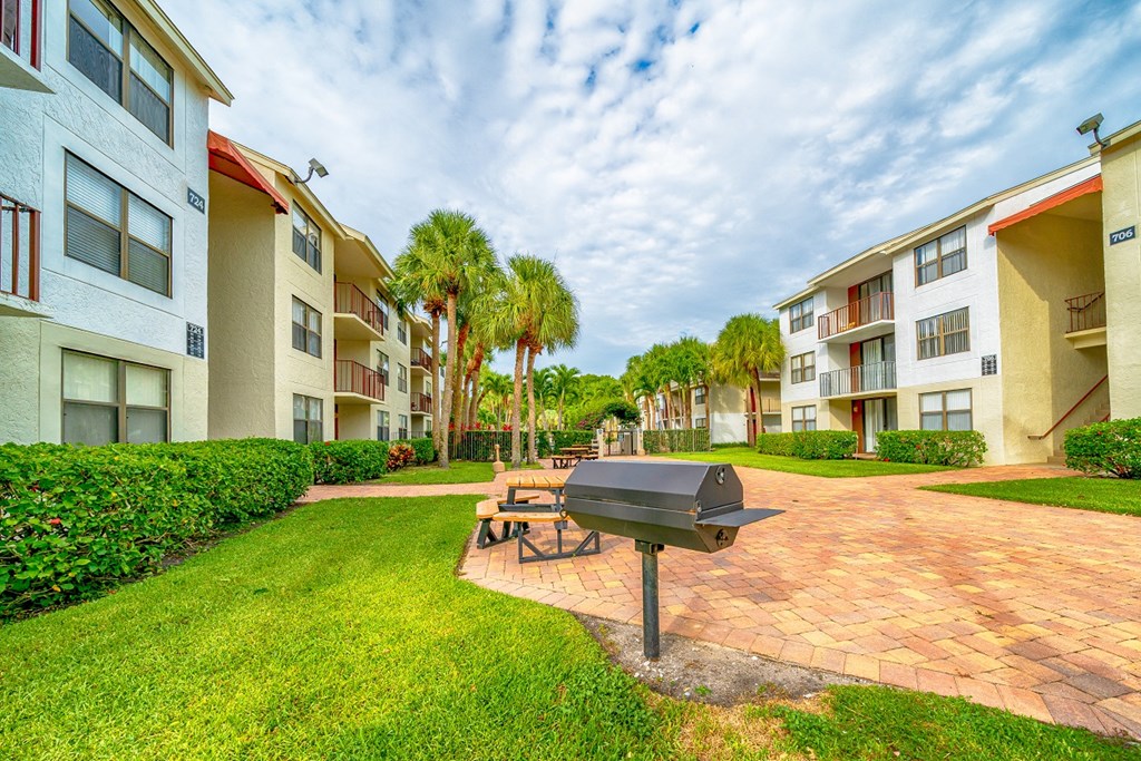 a patio with a grill and a picnic table in front of apartment buildings