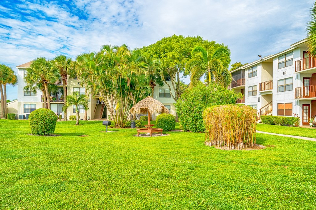 a green yard with palm trees in front of an apartment building