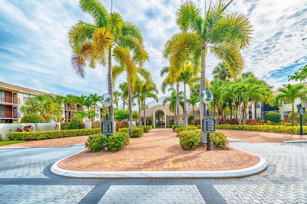 a courtyard with palm trees and a building in the background