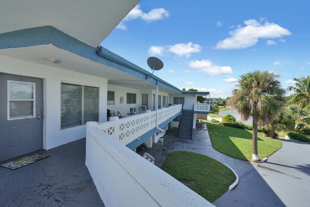 a view of a building with a balcony and a palm tree in front of it