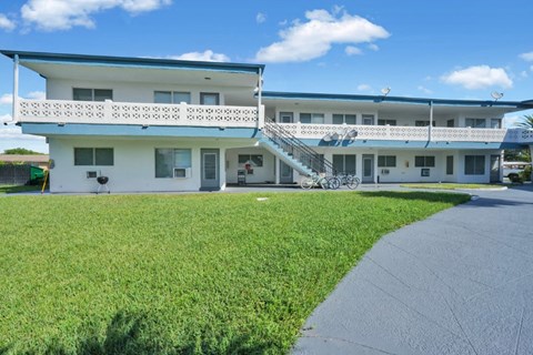 a large white building with a blue roof and a grassy area in front of it