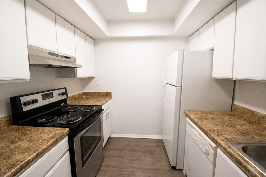 a kitchen with white cabinets and stainless steel appliances and granite counter tops at Red Bay Apartment Complex, Jacksonville, FL
