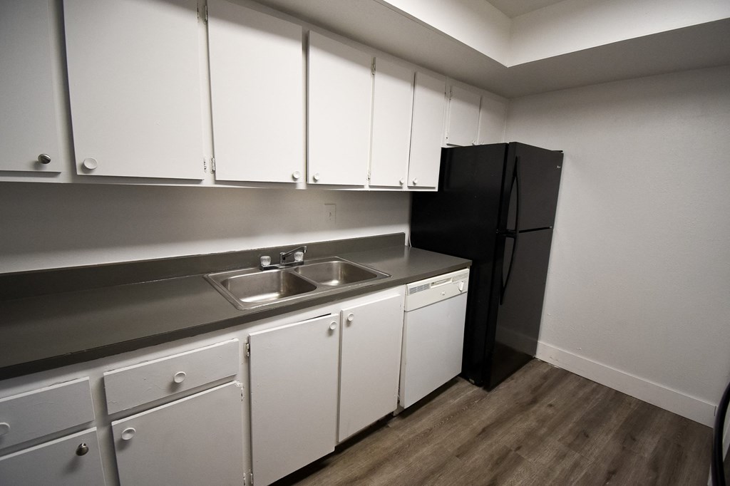 a kitchen with white cabinets and a black refrigerator