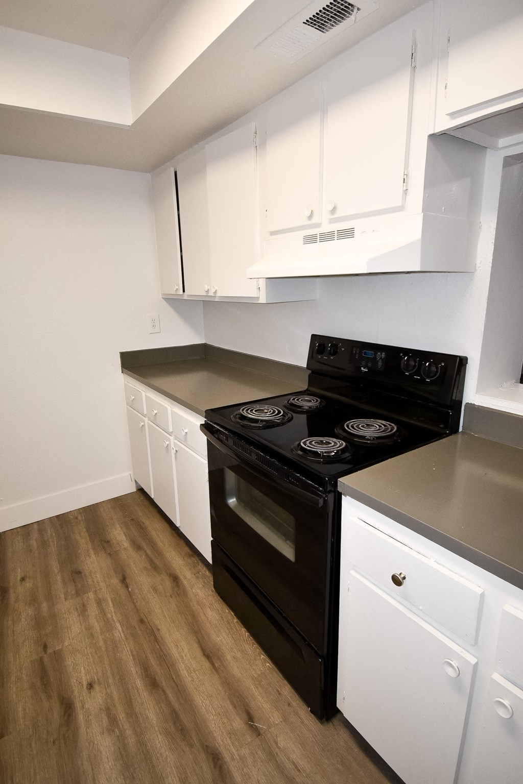 an empty kitchen with white cabinets and a black stove