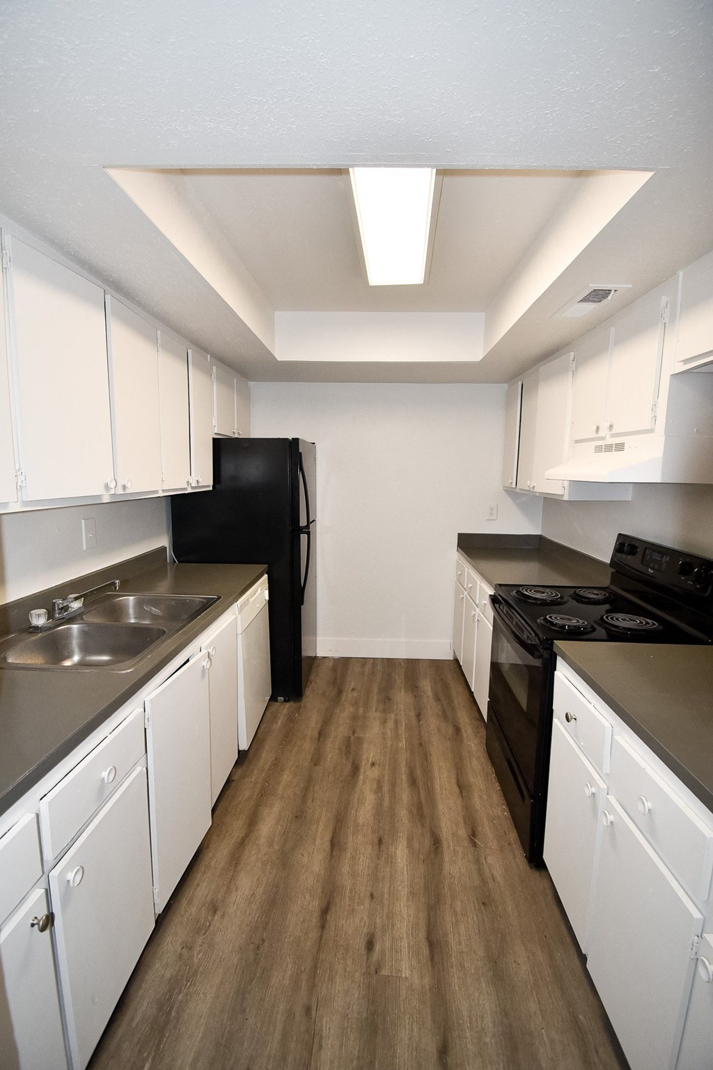 an empty kitchen with white cabinets and a black stove and refrigerator