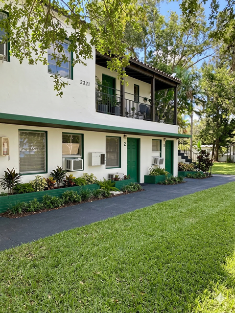 A white house with green trim and a balcony.