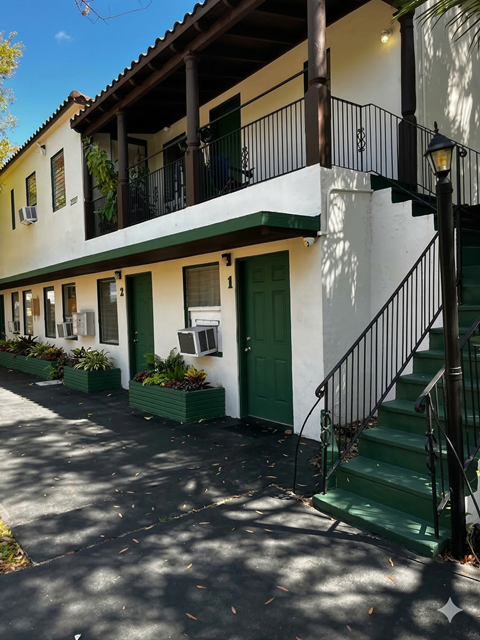 A white building with green doors and a green staircase.
