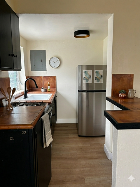 A kitchen with a stainless steel refrigerator and wooden countertops.