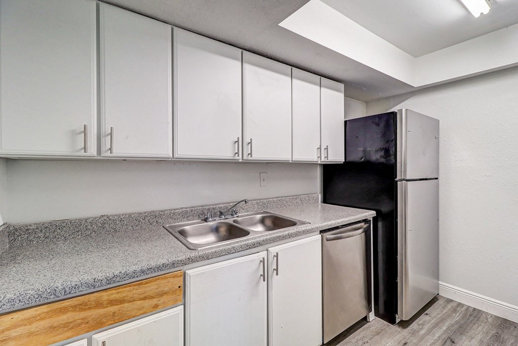 a kitchen with white cabinets and a stainless steel refrigerator