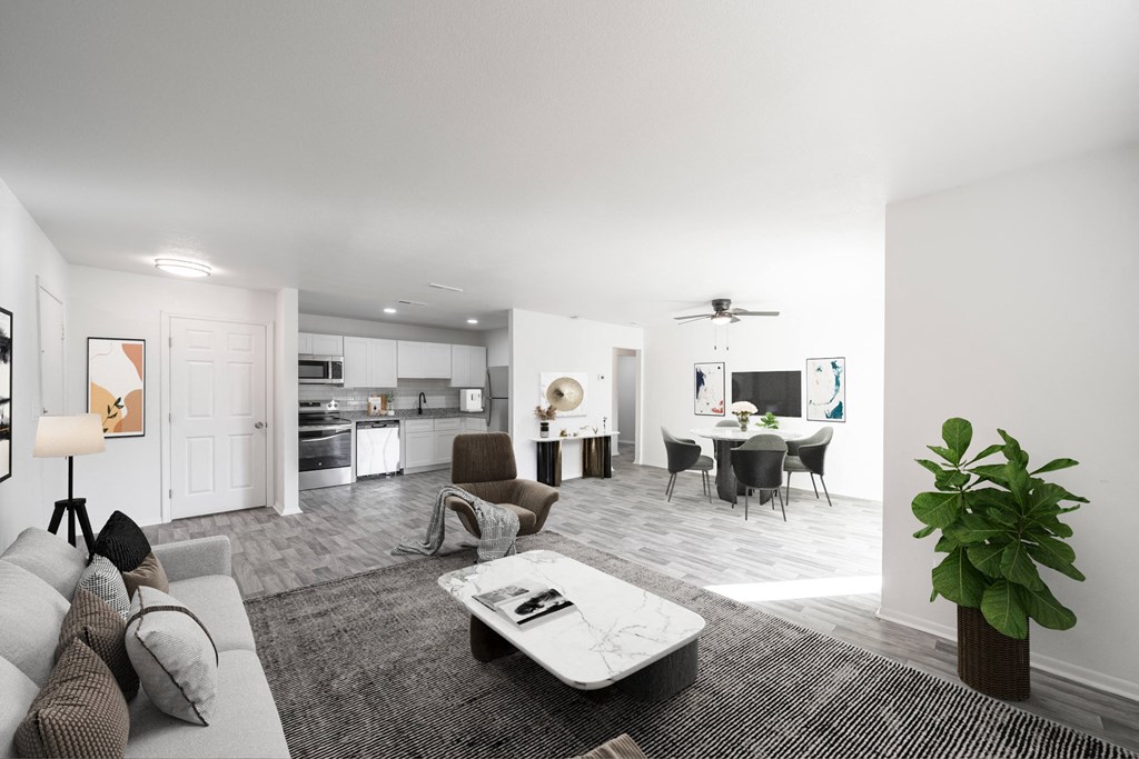 A modern living room with a grey sofa, a coffee table, and a dining area in the background. at Red Bay Apartment Complex, Jacksonville, FL, 32211