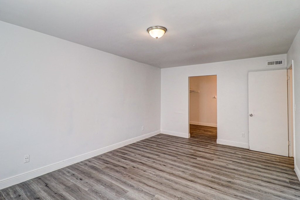 a bedroom with hardwood floors and white walls