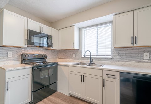 A kitchen with a black oven and white cabinets.