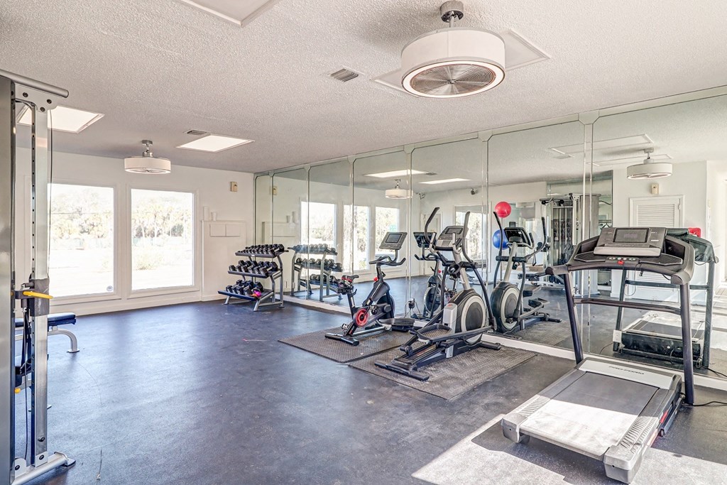a fitness room with cardio equipment and mirrors at Red Bay Apartment Complex, Jacksonville, FL