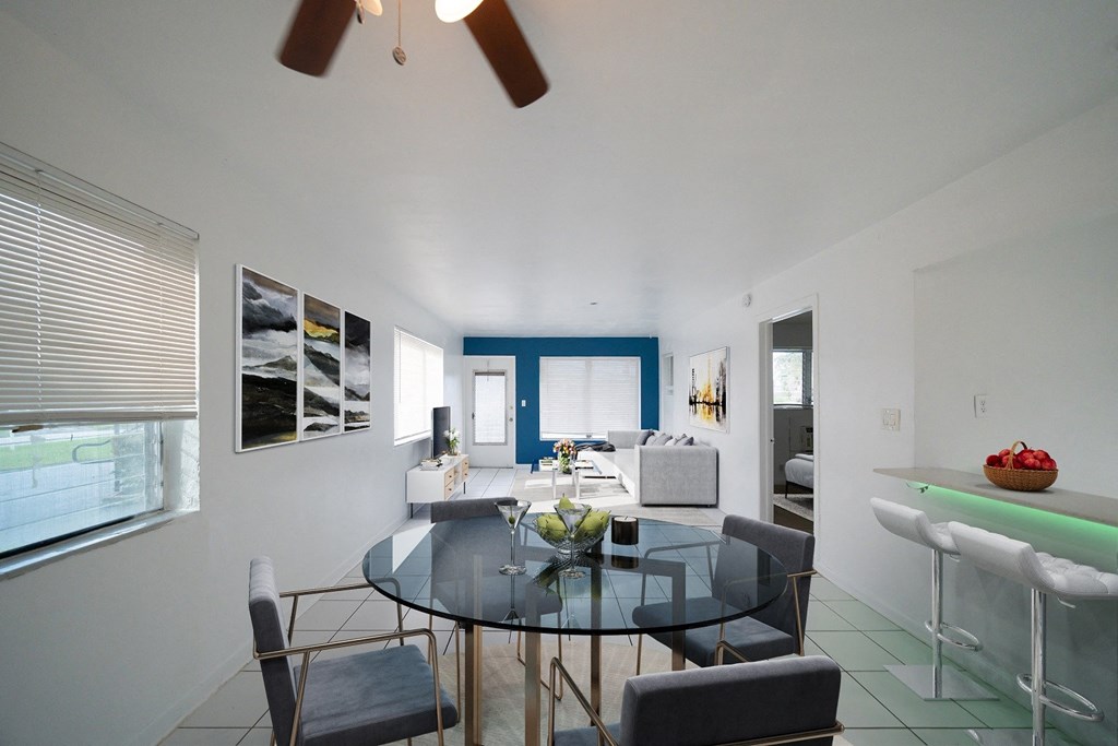 a dining area with a glass table and chairs and a living room with a couch and a