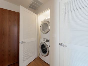 A white washing machine is in a small laundry room at Chateau on Wells, Chicago, 60654