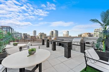 A rooftop patio with a table and chairs overlooking a city skyline at Chateau on Wells, Illinois, 60654