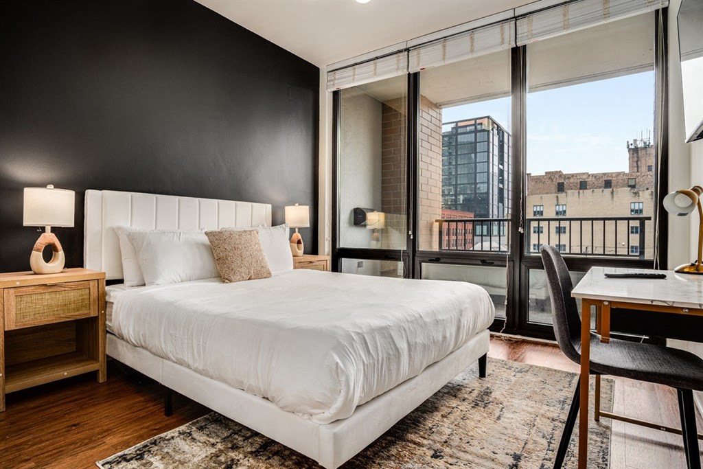 A bedroom with a large bed, a desk, and a chair.