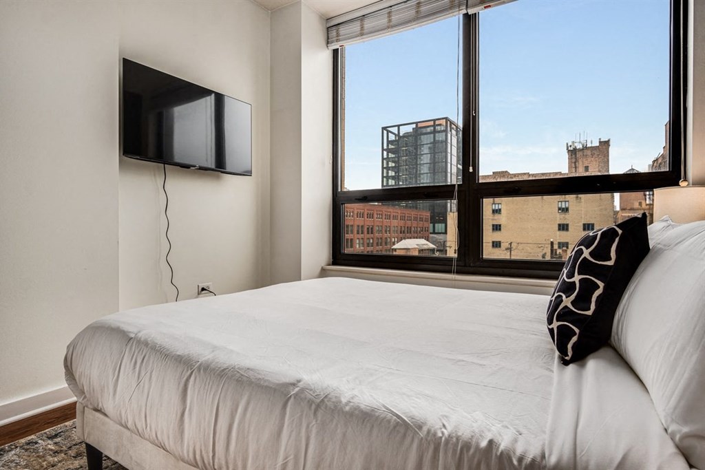 A bedroom with a large bed and a flat screen TV mounted on the wall.