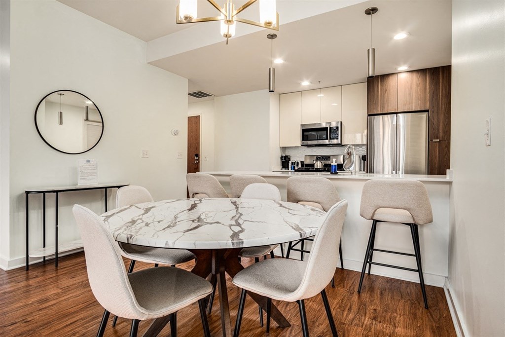 A modern dining room with a round mirror and a marble table.