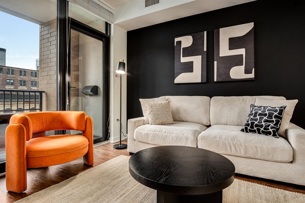 A living room with a white couch and an orange chair.