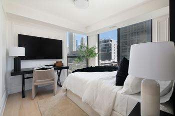 a bedroom with a bed and a desk and a large tv at Chateau on Wells, Illinois