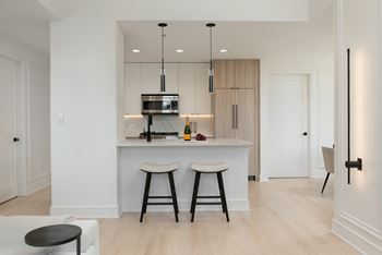 a kitchen with white cabinets and a bar with two stools at Chateau on Wells, Chicago, Illinois