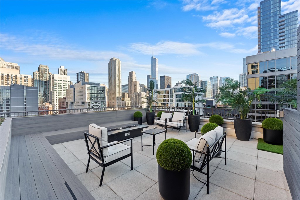 A rooftop patio with chairs and tables overlooking a city skyline at Chateau on Wells, Chicago