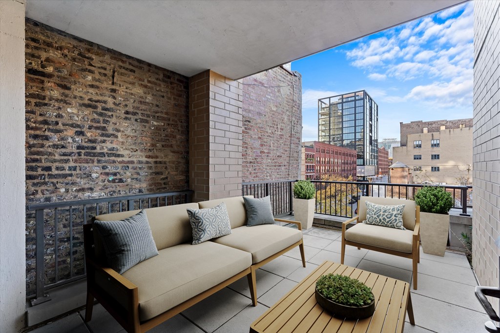 A balcony with a couch, chairs, and a table with a plant on it at Chateau on Wells, Chicago, 60654