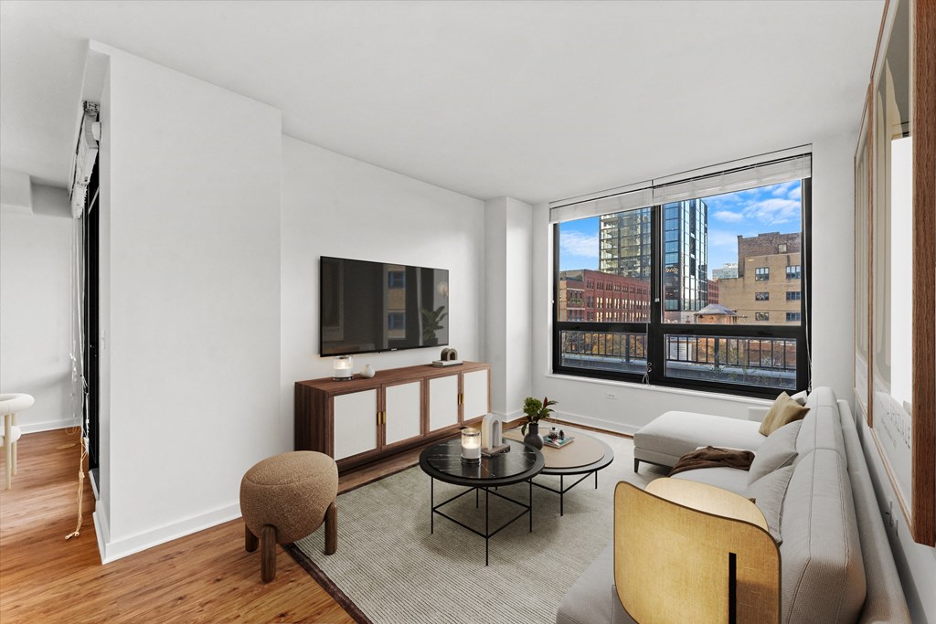 A living room with a brown ottoman, a black coffee table, and a white couch at Chateau on Wells, Illinois, 60654