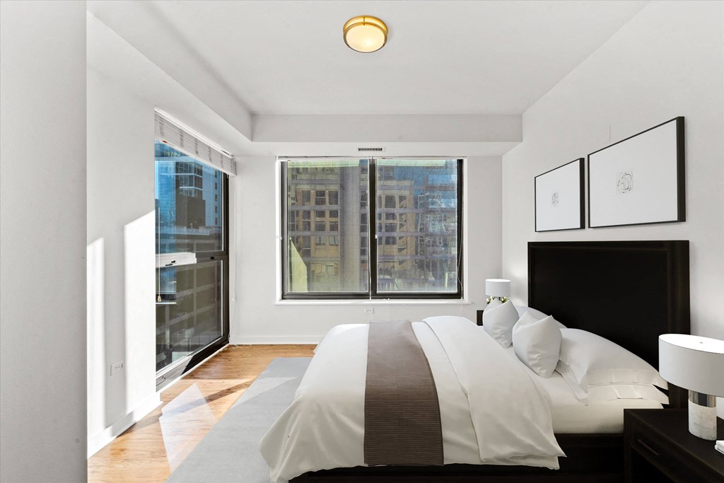 A bedroom with a large bed and a window overlooking a cityscape at Chateau on Wells, Chicago, 60654
