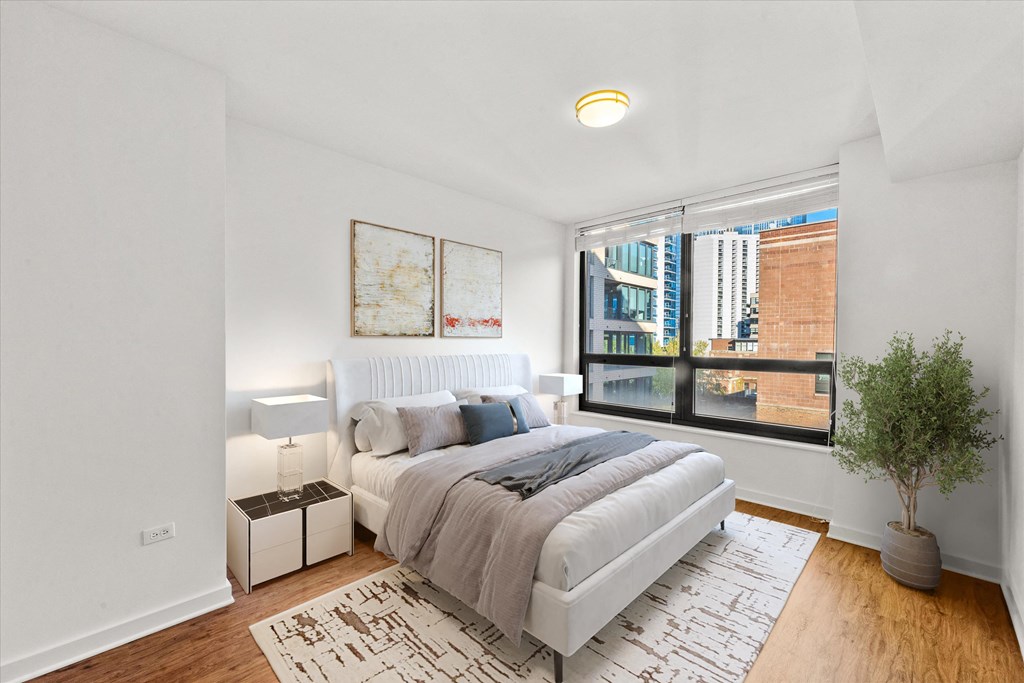 A bedroom with a large bed and a view of a cityscape through the window at Chateau on Wells, Chicago, IL