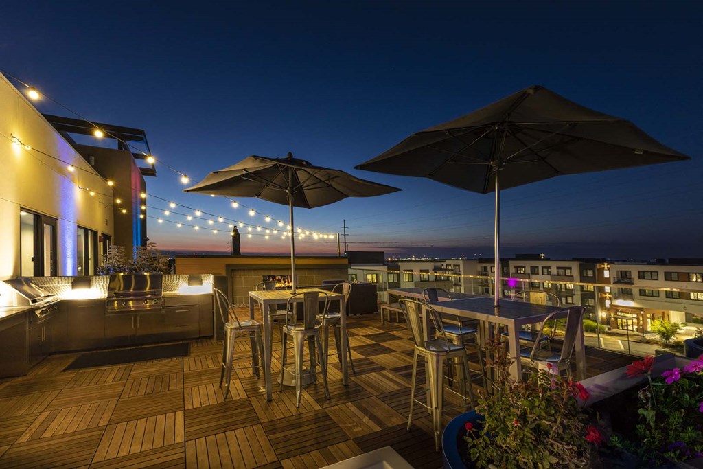 a rooftop bar with tables and chairs and umbrellas