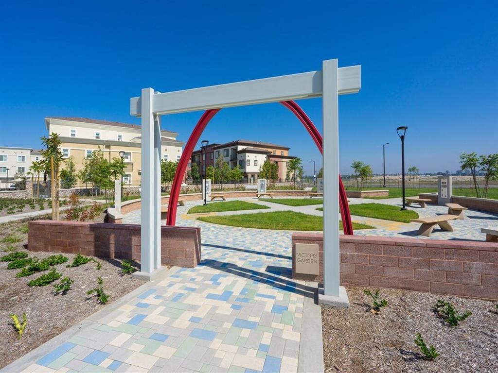 a white arch in a park with a building in the background