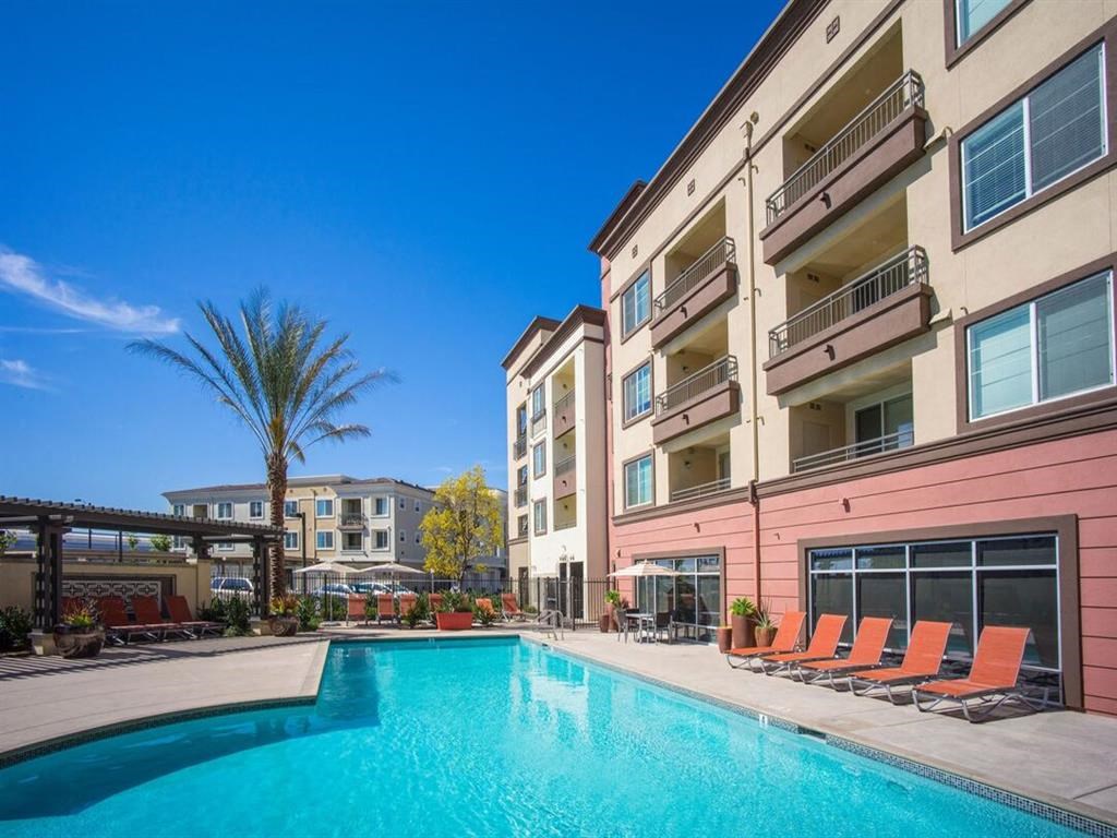 a swimming pool with chairs around it and a building in the background