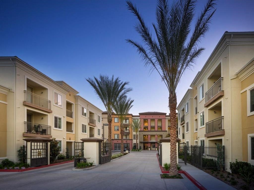 an exterior view of an apartment complex with a driveway and palm trees