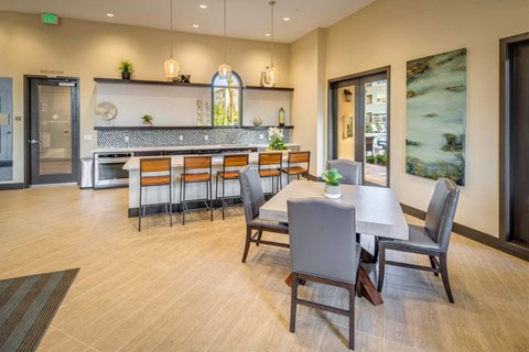 a dining area with a table and chairs and a kitchen in the background