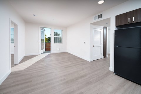 a living room with white walls and a black refrigerator