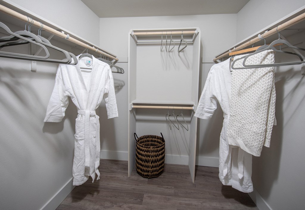a walk in closet with a white robe hanging on the wall
