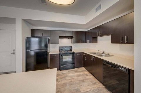 A kitchen with dark brown cabinets and a black fridge.