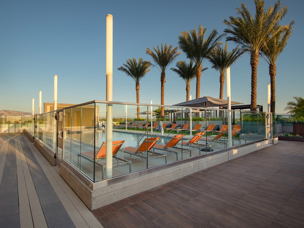 a pool with orange lounge chairs and palm trees in the background
